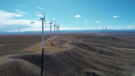 Multiple-windmills-with-moving-blades-placed-in-a-straight-line-on-an-elevated-landscape