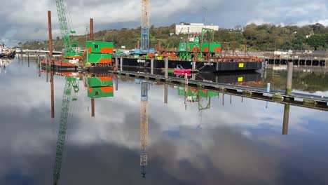 Barcaza-De-Construcción-En-El-Río-Suir-Construyendo-Un-Puente-Peatonal-En-Una-Tranquila-Mañana-De-Invierno-Con-Sombras-Sobre-Las-Tranquilas-Aguas-Durante-La-Marea-Llena