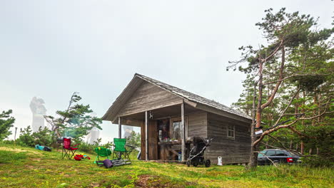 Low-angle-shot-over-tourists-enjoying-a-trip-to-a-wooden-cottage-along-rural-countryside-in-timelapse-throughout-the-day