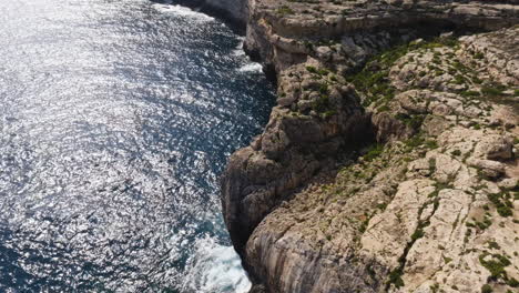 Drone-shot-flying-along-the-rocky-coastline-of-the-Malta-island,-on-a-sunny-day
