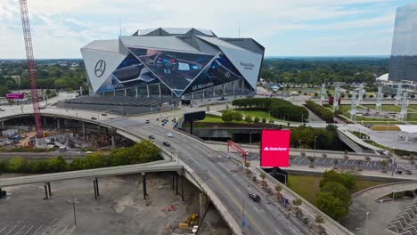 Drone-approaching-shot-of-traffic-on-road-and-Mercedes-Benz-Stadium-in-Atlanta-City,-Georgia