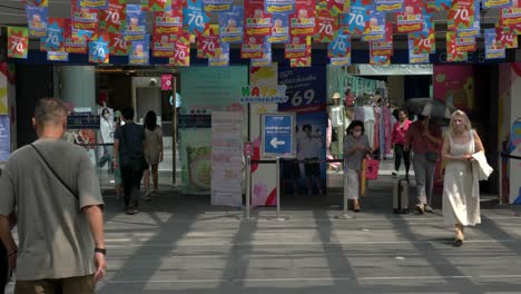 Menschen-Betreten-Oder-Verlassen-Den-Eingang-Des-Modernen-Einkaufszentrums,-Mit-Der-Anzeige-Von-Verkäufen-Bis-Zu-70-%-Am-Terminal-21-Asok,-Das-Sich-An-Der-Kreuzung-Sukhumvit-Und-Asok-In-Bangkok,-Thailand,-Befindet