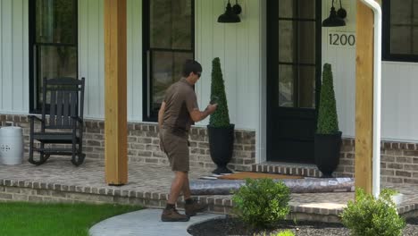 UPS-delivery-man-dropping-off-rug-on-American-house-front-porch
