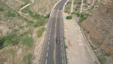 Aerial-tracking-shot:-Elevated-bridge-in-arid-region,-car-driving,-Mexico