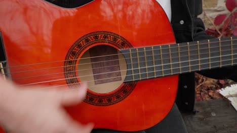 Close-up-hand-rhythm-strums-strings-red-acoustic-guitar