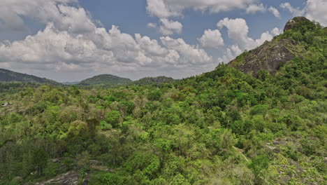 Algama-Len-Viharaya-Sri-Lanka-Luftaufnahme-V1-Filmische-Niedrige-Drohne-überflug-Bewaldeter-Berg,-Aufnahme-Versteckter-Alter-Höhlenbuddhistischer-Tempel-Eingebettet-In-üppigen-Hügeln-–-Aufgenommen-Mit-Mavic-3-Cine-–-April-2023