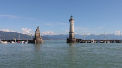 Tour-boat-enters,-leaves-old-Lindau-harbor-past-lighthouse,-lion-statue