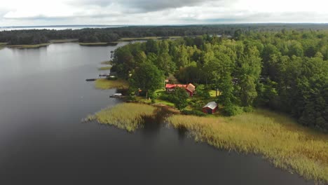 Wooden-cabins-near-lake-at-Piksborg-Sweden-during-day-time,-aerial