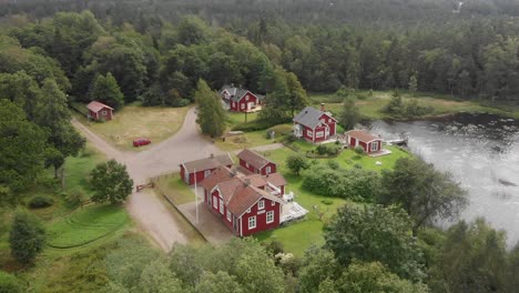 Enthüllen-Sie-Eine-Aufnahme-Traditioneller-Roter-Häuser-In-Piksborg-Lidhult-Schweden,-Luftaufnahme