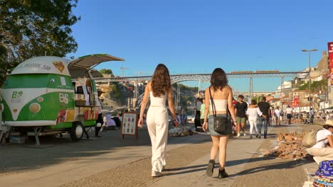 Vila-Nova-De-Gaia,-Portugal:-Menschen,-Die-Auf-Der-Straße-Mit-Der-Brücke-Dom-Luis-I-Im-Hintergrund-über-Den-Fluss-Douro-In-Der-Stadt-Gaia,-Porto,-Portugal,-Spazieren