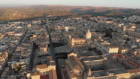 Side-panning-shot-of-famous-roman-catholic-cathedral-in-Noto-during-sunrise,-aerial