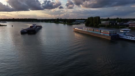 Aerial-view-of-container-shipping-on-Dutch-rivers-at-sunset-with-horizon-clouds