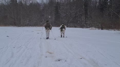 Militärübung-Im-Schneesturm,-Zwei-Soldaten-Fahren-In-Voller-Montur-Ski-Davon
