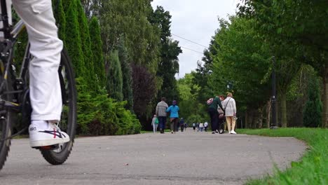 Statische-Aufnahme-Von-Menschen-Und-Fahrrädern-Auf-Einer-Straße-Mitten-Im-Park-In-Der-Stadt-Chorzow-In-Polen-An-Einem-Sonnigen-Tag