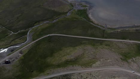 Aerial-tilt-up-shot-of-beautiful-landscape-with-vehicle-on-road-and-Raudasandur-Beach-in-background,-Iceland