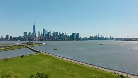 Drohne-Nähert-Sich-Einer-Aufnahme-Des-Liberty-State-Parks-Mit-Manhattan-Und-Der-Skyline-Vor-Blauem-Himmel-Im-Sommer