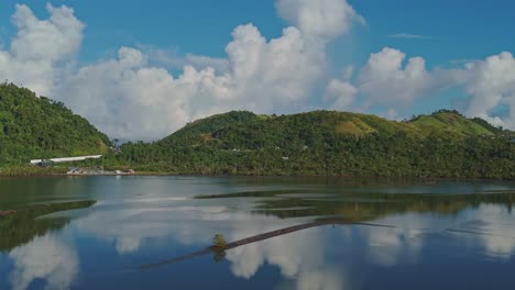A-cinematic-parallax-of-fish-ponds-in-Surigao---Philippines,-used-for-catching-Pasayan-Shrimp,-surrounded-by-lush-hills-and-blue-sky