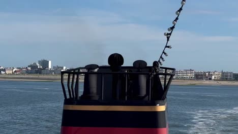 Close-up-shot-of-rising-smoke-of-funnel-on-ferry-ship-on-sea-and-norderney-island-in-Background,-Germany