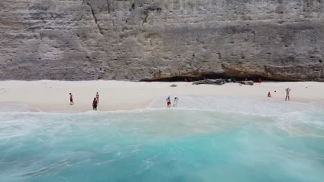 Olas-Y-Aguas-Cristalinas-De-La-Playa-De-Diamantes-En-Nusa-Penida-Con-Turistas-Nadando-Y-Relajándose
