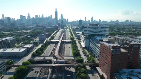 Rush-Medical-Center-beside-a-bustling-freeway,-with-the-Chicago-city-skyline-stretching-beyond,-bathed-in-morning-light