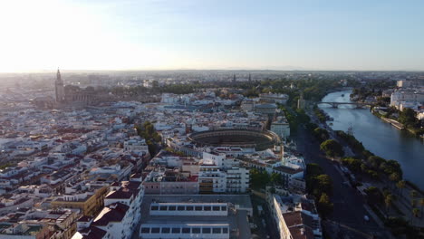 Vista-Aérea-Al-Atardecer-De-La-Plaza-De-Toros,-El-Río-Guadalquivir-Y-La-Catedral-De-Sevilla