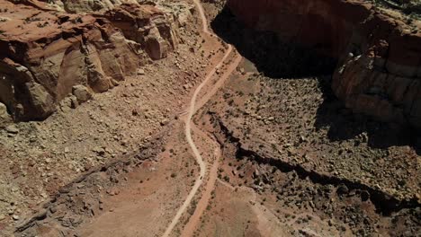 A-cinematic-overhead-Drone-Shot-of-Capitol-Reef-National-Park,-with-a-road-cutting-through-it-and-the-scenic-mountain-towards-the-end