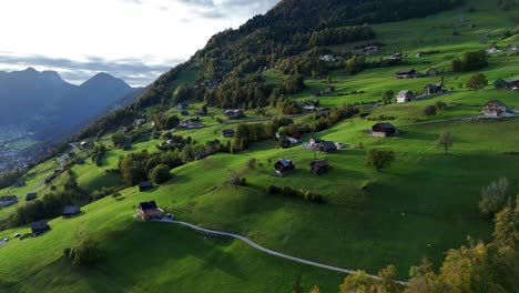 Aerial-view-of-green-mountain-with-swiss-neighborhood-in-Amden-during-sunny-day-in-Switzerland