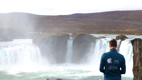 Man-standing-on-the-edge-of-a-majestic-waterfall-in-Iceland