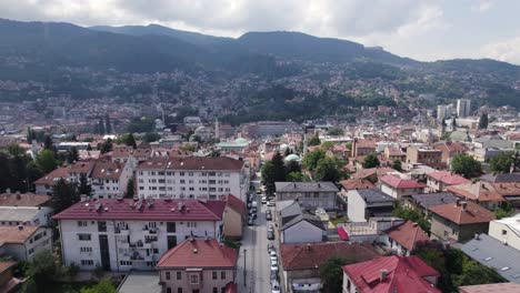 Aéreo:-Paisaje-Urbano-De-Sarajevo,-Bosnia-Y-Herzegovina-Con-Fondo-Montañoso