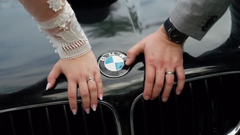 Manos-De-Recién-Casados-Con-Anillos-De-Boda-En-El-Capó-Del-Coche-BMW