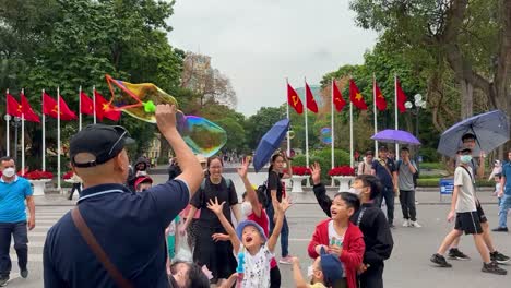 Man-Blows-Bubbles-in-the-street,-Children-happy-popping-blown-bubbles-in-the-street