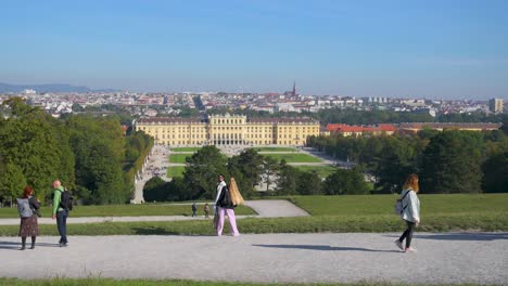 Touristen,-Die-An-Einem-Sonnigen-Herbstmorgen-Im-Park-Von-Schloss-Schönbrunn-Spazieren-Gehen-Und-Das-Schloss-Und-Das-Stadtbild-Von-Wien-Beobachten,-Wien,-Österreich---Oktober-2023