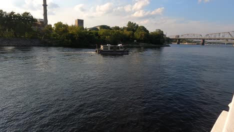 Boat-on-Ottawa-River-with-bridges-and-tower-backdrop,-Canada
