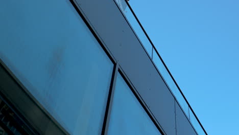 Close-up-of-modern-building's-glass-facade-against-blue-sky