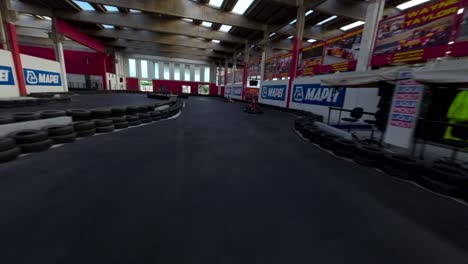 Crazy-fpv-drone-flying-over-pilots-driving-Go-Kart-on-indoor-and-outdoor-track-for-racing