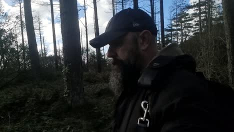 Bearded-man-wearing-New-York-baseball-cap-travelling-through-woodland-forest-wilderness-alone