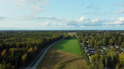 Drone-shot-over-a-deserted-road-with-forests-on-the-sides-and-a-quiet-and-lonely-village-on-a-clear-and-sunny-day,-Kerava-Finland