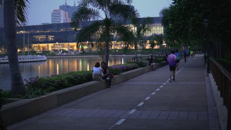 People-along-the-pathway-of-Benjakitti-Park-in-the-city-of-Bangkok,-Thailand-handheld-wide-angle