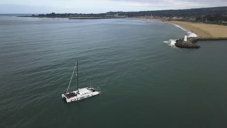 Drone-shot-circling-a-catamaran-on-the-coast-of-Santa-Cruz,-in-California,-USA