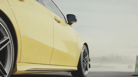 Low-close-up-view-of-new-yellow-Mercedes-car-stop-at-wet-safety-track-start-line