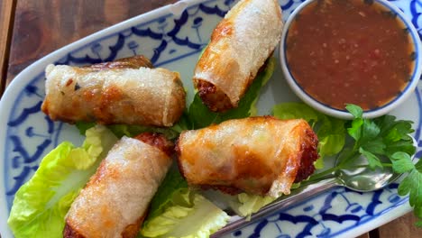 Traditional-spring-rolls-on-lettuce-with-sweet-chili-sauce-in-Thai-restaurant,-asian-food,-starter-for-lunch,-4K-top-view-shot