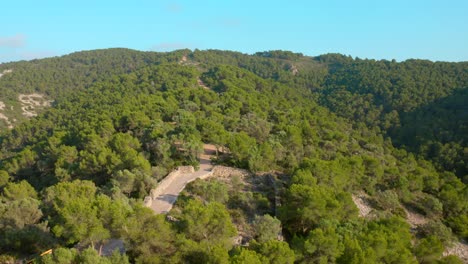 Aerial-drone-shot-over-green-vegetation-covering-hilly-terrain-in-Serra-d'Irta-natural-park,-Costa-del-Azahar,-Spain-at-daytime