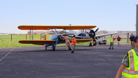 Pilot-Eines-Boeing-Stearman-75-Oldtimer-Trainingsflugzeugs-Aus-Dem-Zweiten-Weltkrieg,-Der-Den-Propeller-Dreht,-Bevor-Er-Den-Motor-Auf-Einer-Flugshow-Am-Centennial-Airport-In-Colorado-Startet