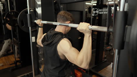Strong-Muscular-Adult-Man-Doing-Shoulder-Press-In-Smith-Machine-at-Gym---close-up