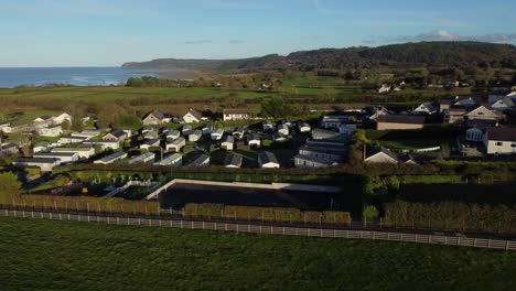 Aerial-view-flying-towards-scenic-Welsh-caravan-holiday-home-park-overlooking-peaceful-bay-coastline