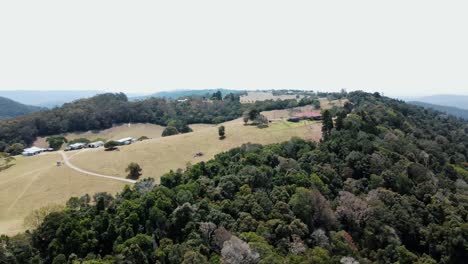 Drone-aerial-over-a-lush-Australian-native-mountain-with-trees-that-has-been-partly-settled-on