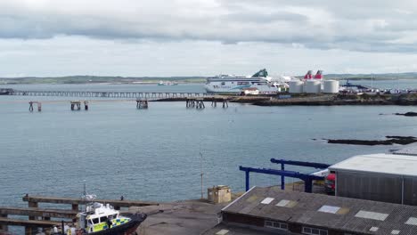 Aerial-view-dolly-across-Holyhead-harbour-with-police-boat-and-Irish-ferry-ship-in-Welsh-port-terminal