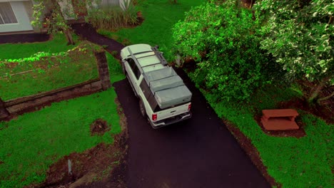 Ascending-aerial-of-back-house-yard,-track-van-located-and-parked-in-front-of-the-house,-daytime-capture,-suburban-lifestyle-concept