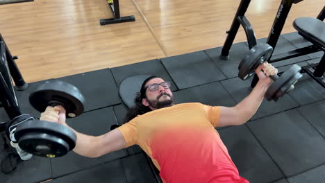 Latin-man-with-beard-and-long-hair-performing-crucifix-exercise-with-dumbbells