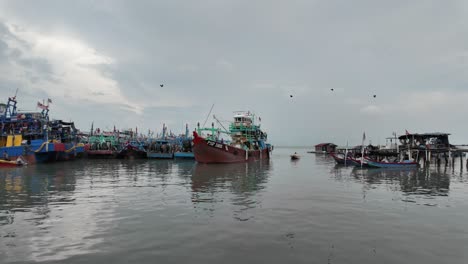 Belebter-Küstenhafen-Mit-Bunten-Fischerbooten-Und-Der-Malaysischen-Flagge,-Die-Den-Standort-Vor-Einem-Bewölkten-Himmel-Anzeigt